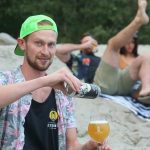 Backcountry Brewing | Blew Out My Flip Flop Pina Colada Sour - Man pouring can in glass on a beach
