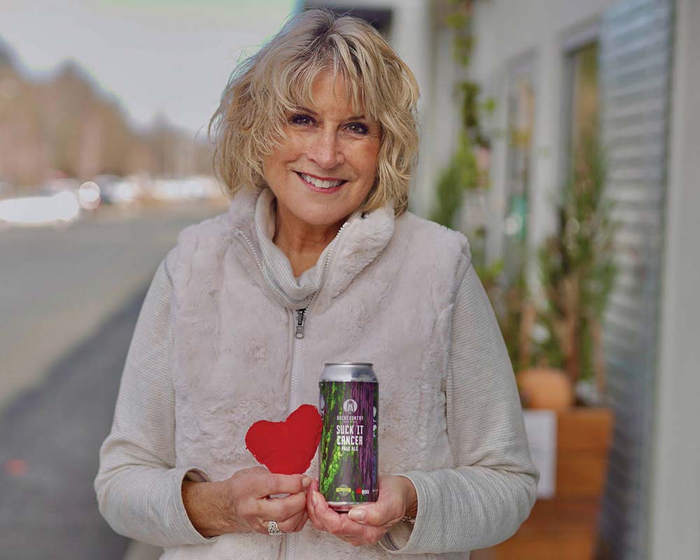 Maureen Thom holds a can of Suck it Cancer Pale Ale and a heart created by her son Michael ‘Chili’ Thom when he was in kindergarten.