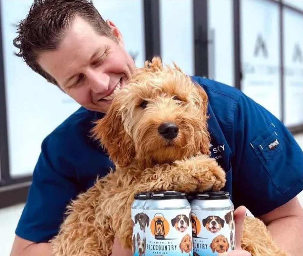 Squamish Reporter, October 2021 | Man with dog and pack of Throw Me A Frickin' Bone beer by Backcountry